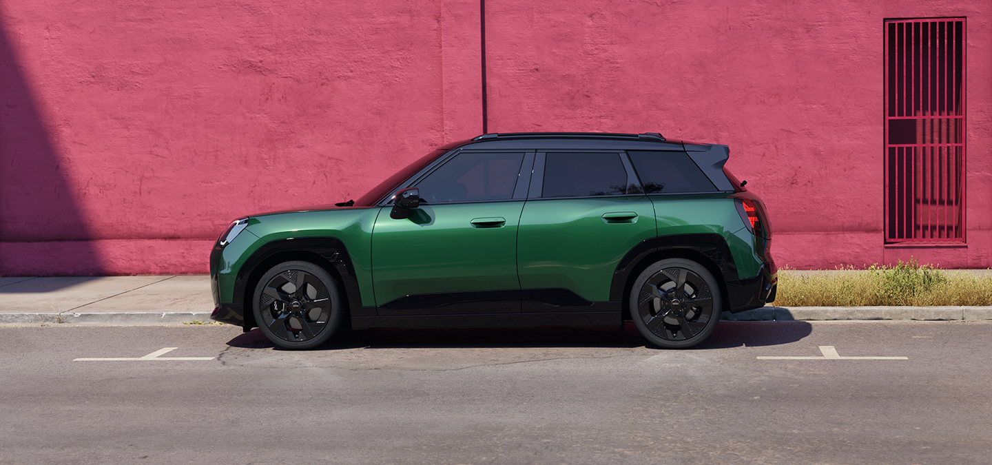 A tisztán elektromos MINI Aceman oldalnézetben, British Racing Green színben, fekete tetővel.