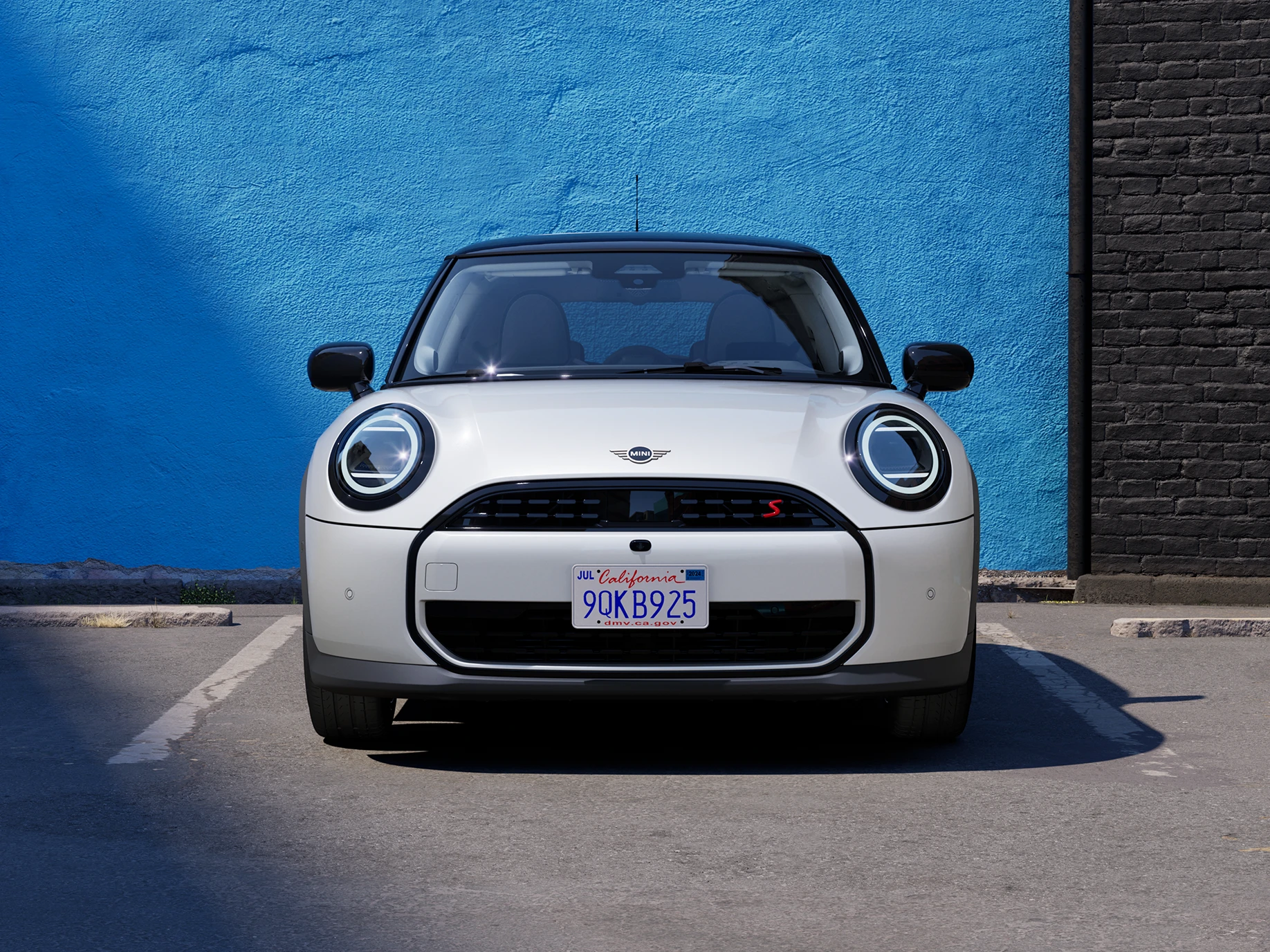 Egy parkoló MINI Cooper elölnézetből, Nanuq Fehér színben, fekete tetővel.