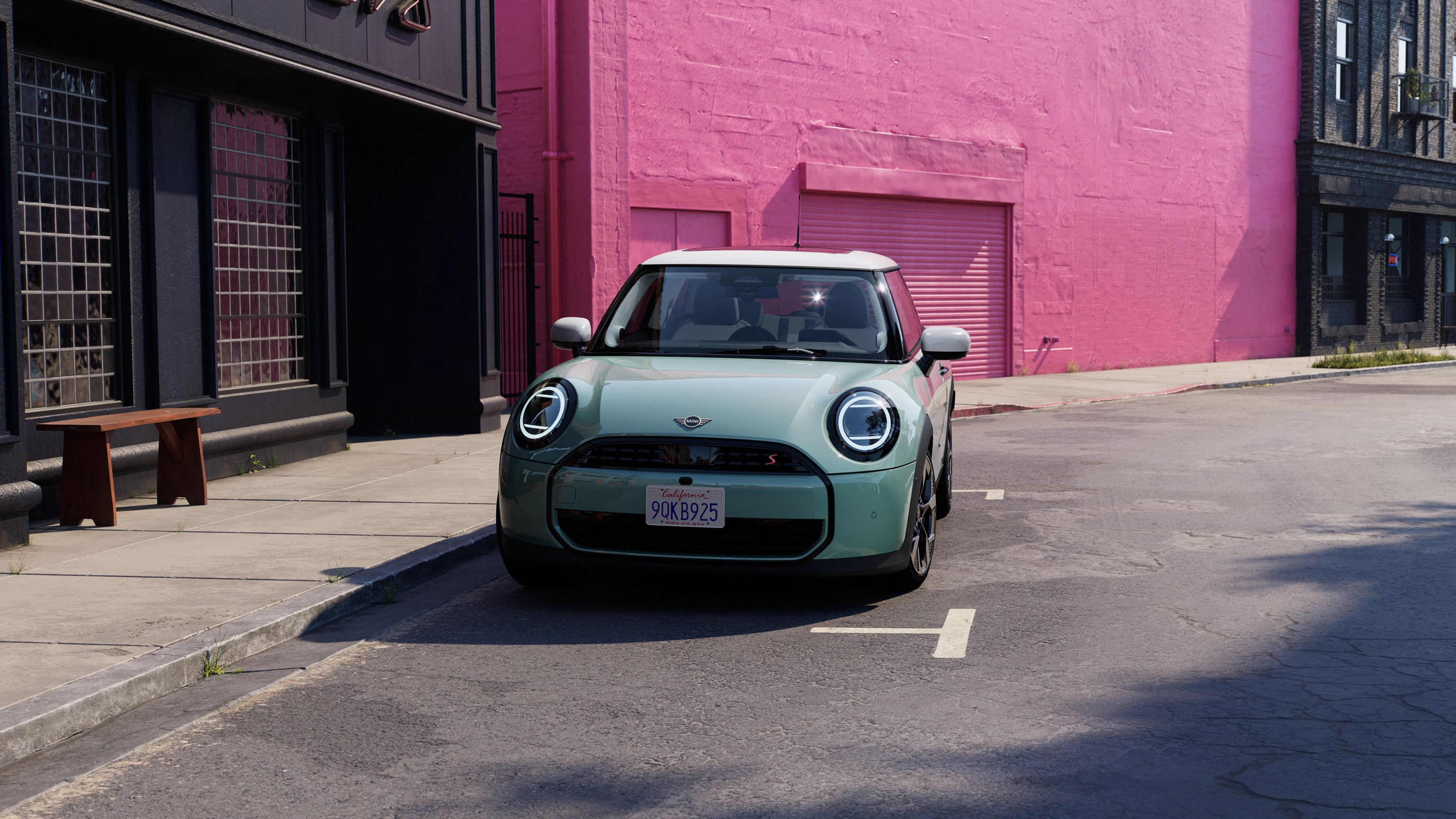 Egy rózsaszín fal előtt az utcán parkoló MINI Cooper elölnézetből, Ocean Wave Green színben, fehér tetővel