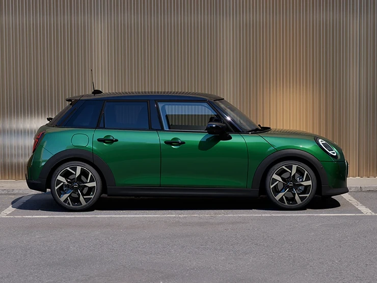 Az 5 ajtós MINI Cooper oldalnézetből, British Racing Green színben, fekete tetővel.