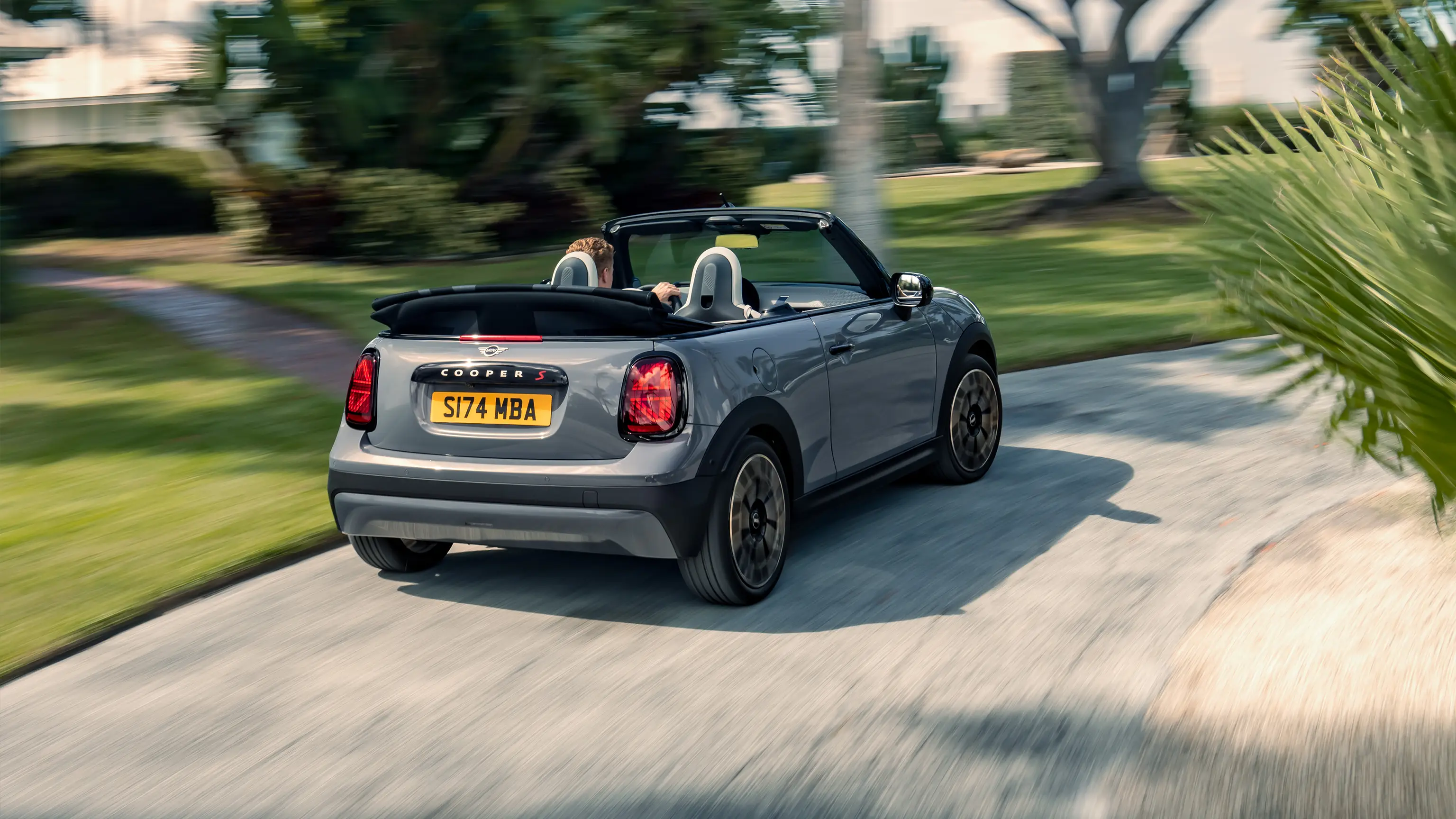 Egy Copper Grey fényezésű MINI Cooper Cabrio menet közben, hátulról 