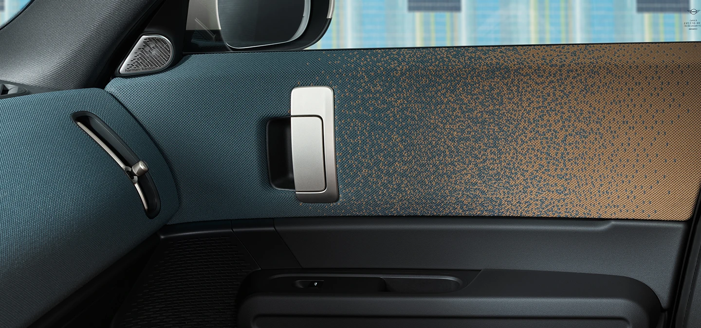 A tisztán elektromos MINI Countryman belső dizájnja közelről, az ajtóra és a műszerfalra összpontosítva.