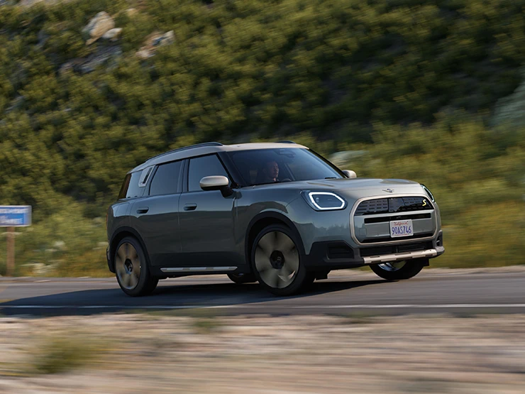A tisztán elektromos MINI Countryman oldalnézete, Smokey Green színben, Vibrant Silver színű tetővel.