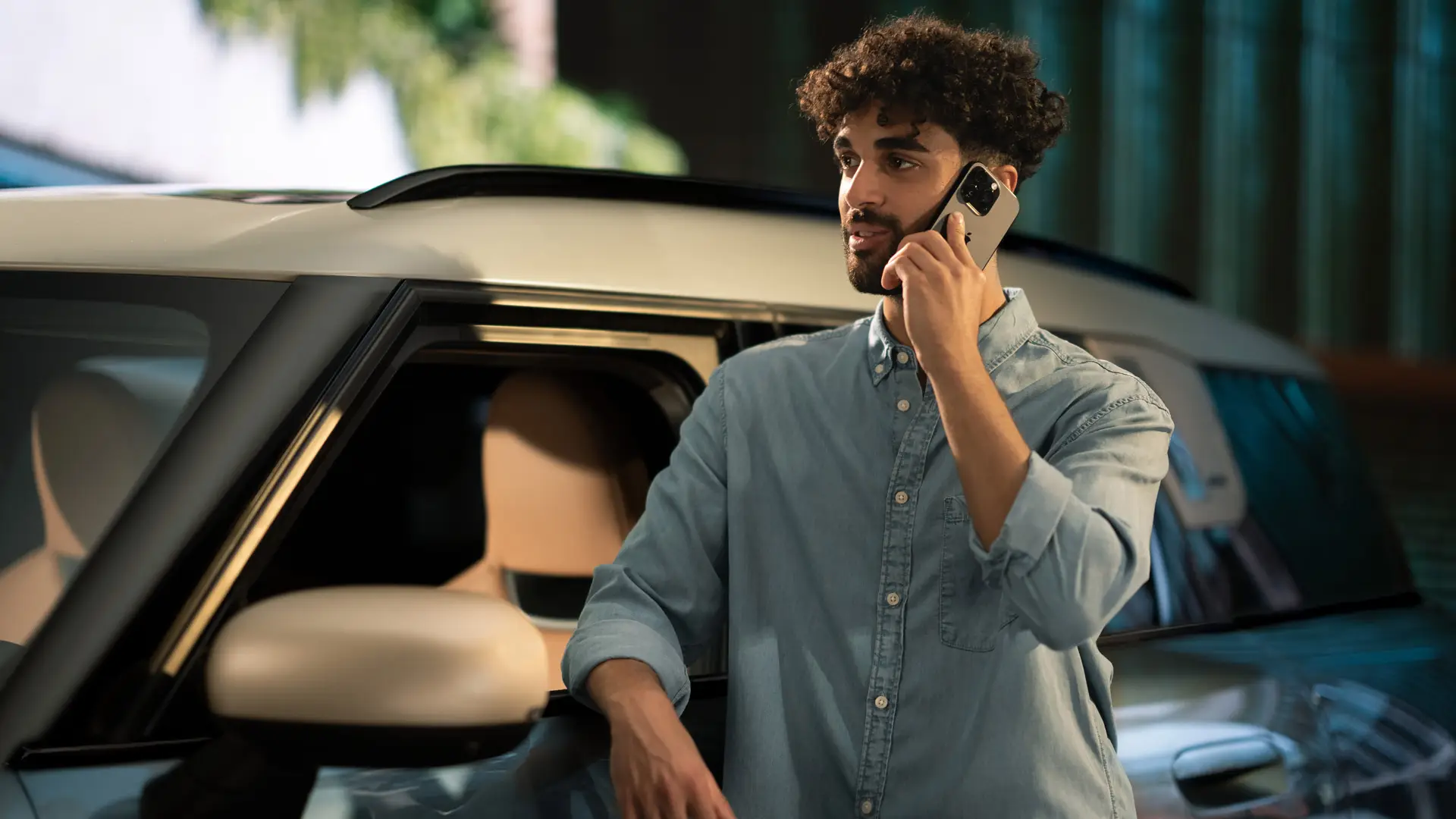 MINI proaktív gondoskodás – egy férfi a MINI-je mellett áll, és a márkaszerviz tanácsadójával beszél telefonon.