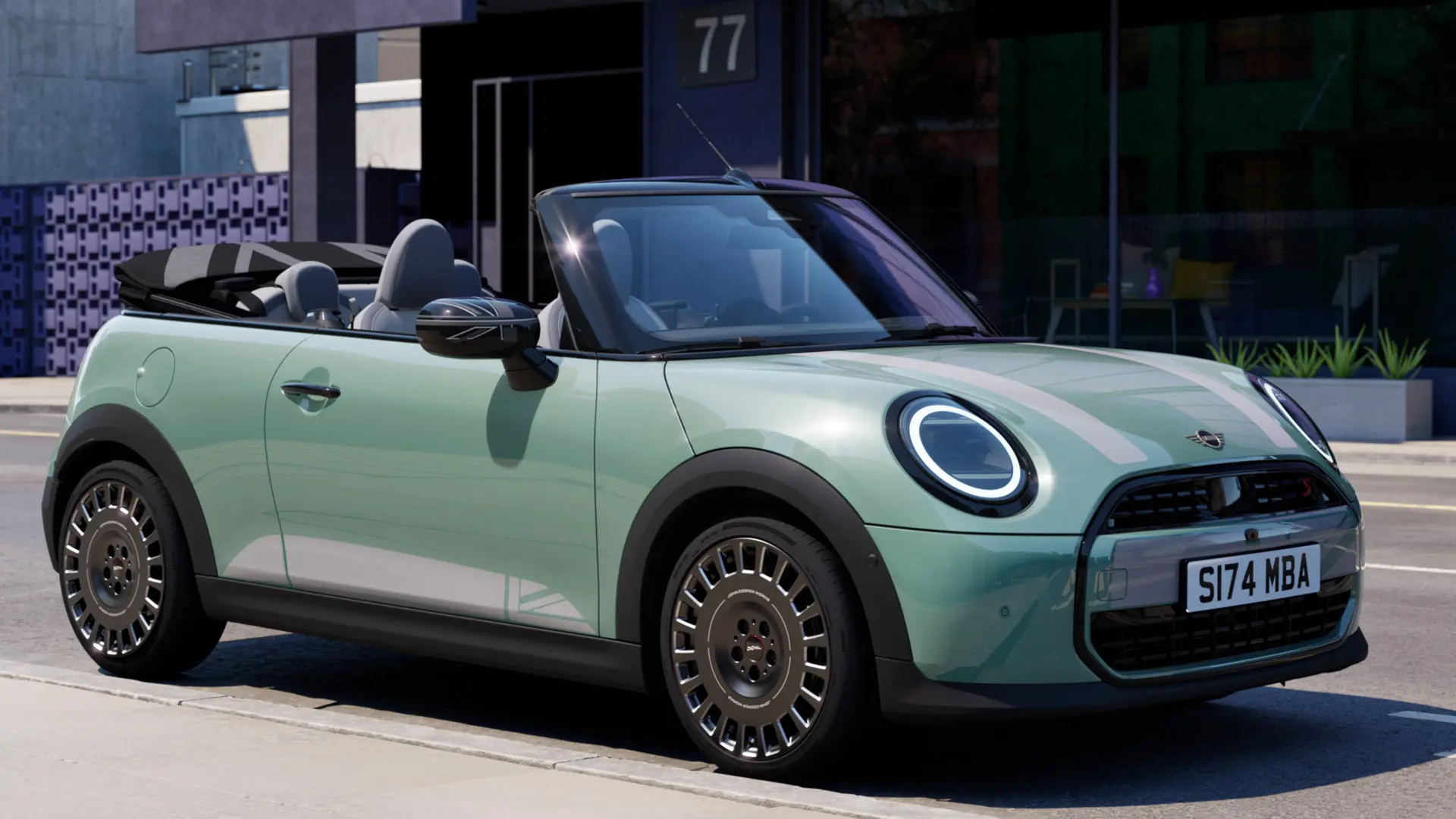 A MINI Cabrio elülnézete Ocean Wave Green színben, fehér MINI Heritage motorháztető matricáival. 