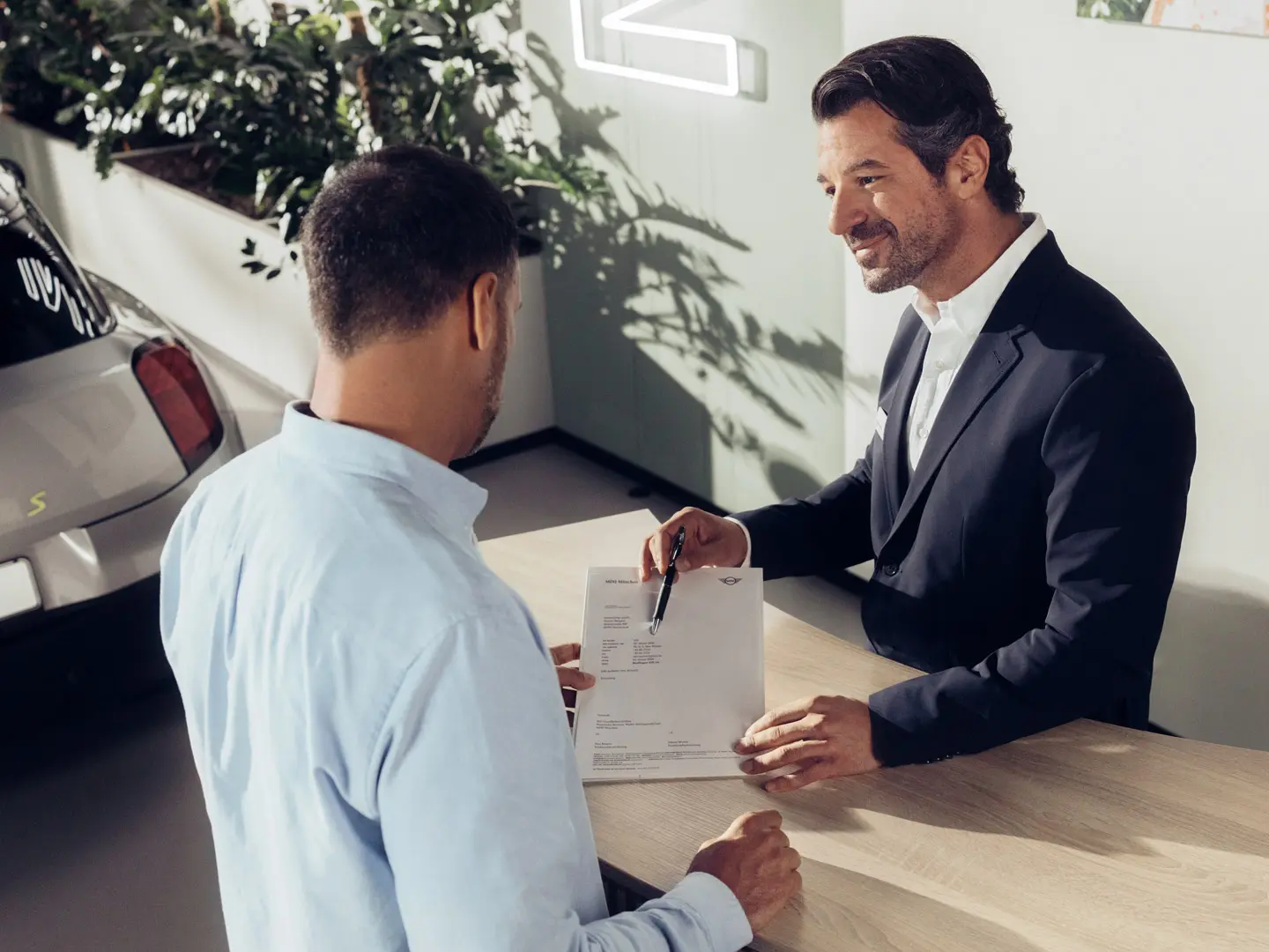 Egy MINI Partner szervizasszisztense tanácsot ad egy ügyfélnek a MINI gumiabroncs-biztosítási lehetőségekről.