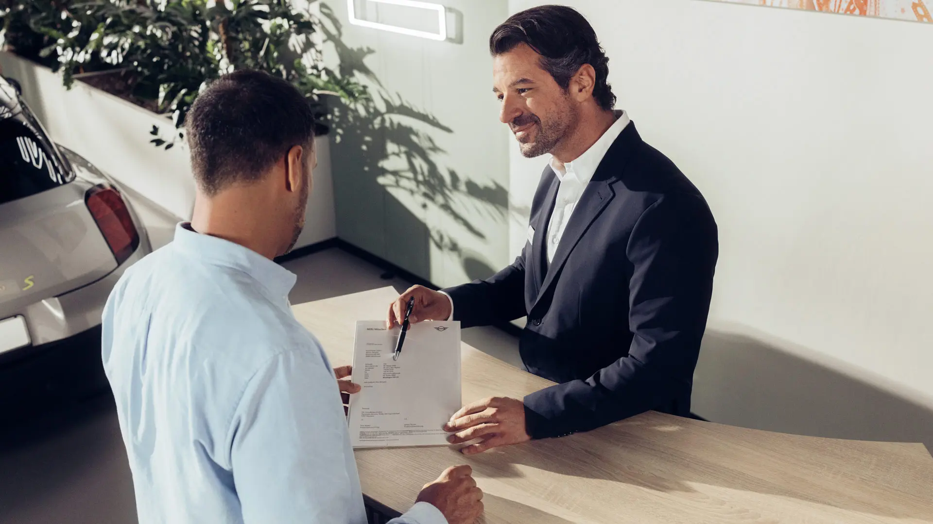 Egy MINI Partner szervizasszisztense tanácsot ad egy ügyfélnek a MINI gumiabroncs-biztosítási lehetőségekről.