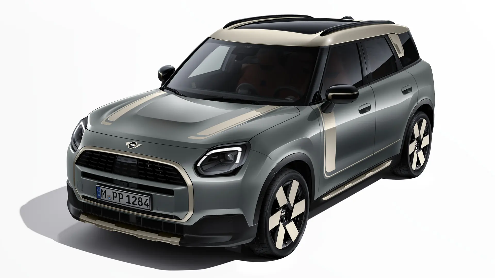 Egy Smokey Green fényezésű, Vibrant Silver MINI Favoured matricákkal ellátott elektromos MINI Countryman rézsútos nézetből.