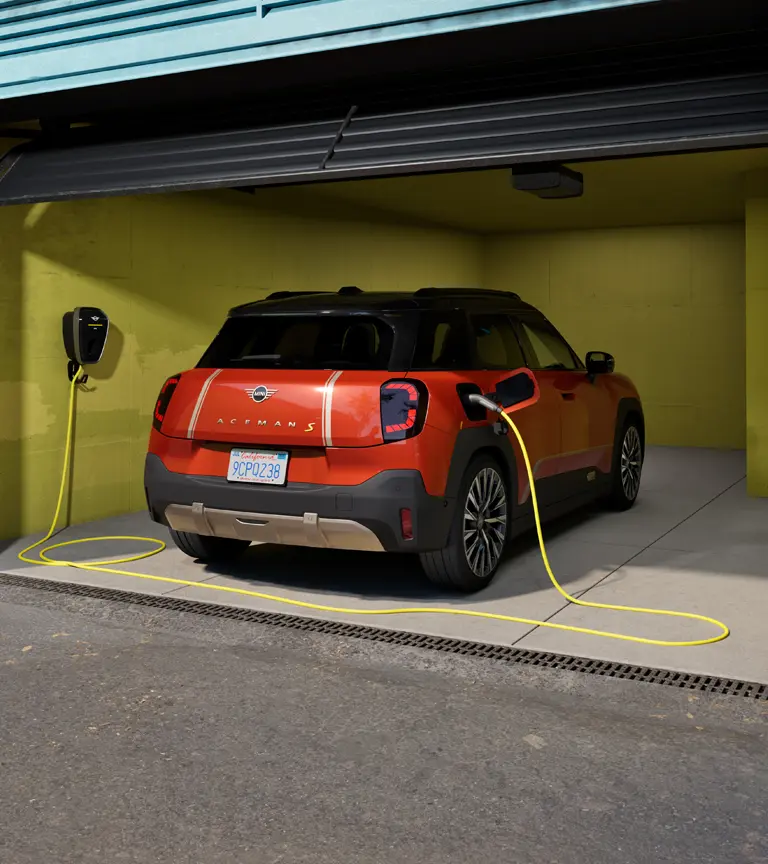 Egy tisztán elektromos hajtású, garázsban álló, MINI Wallbox Plus készülékről töltött MINI Aceman hátulról.