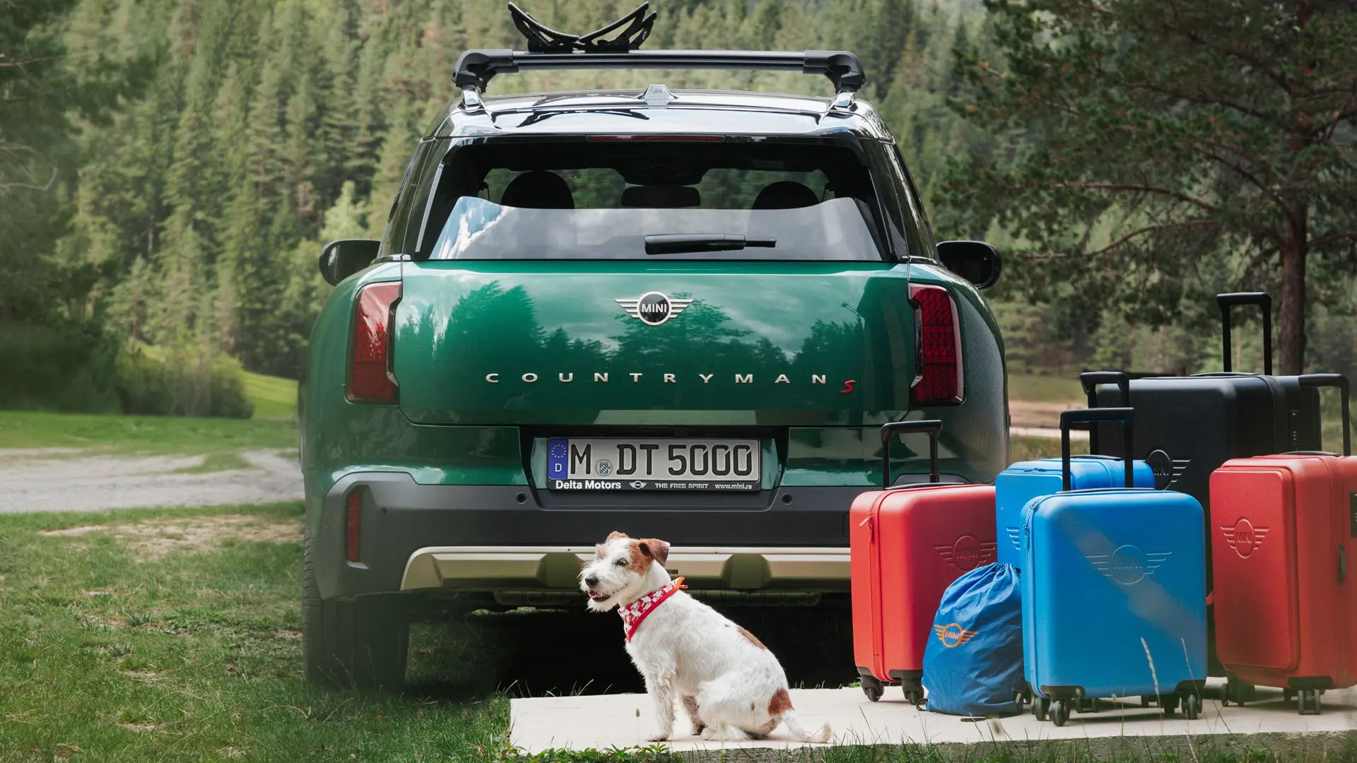 Egy zöld, számos, a MINI Lifestyle áruházban megvásárolható szállítási tartozékkal ellátott MINI Countryman egy Jack Russell kutya társaságában. 