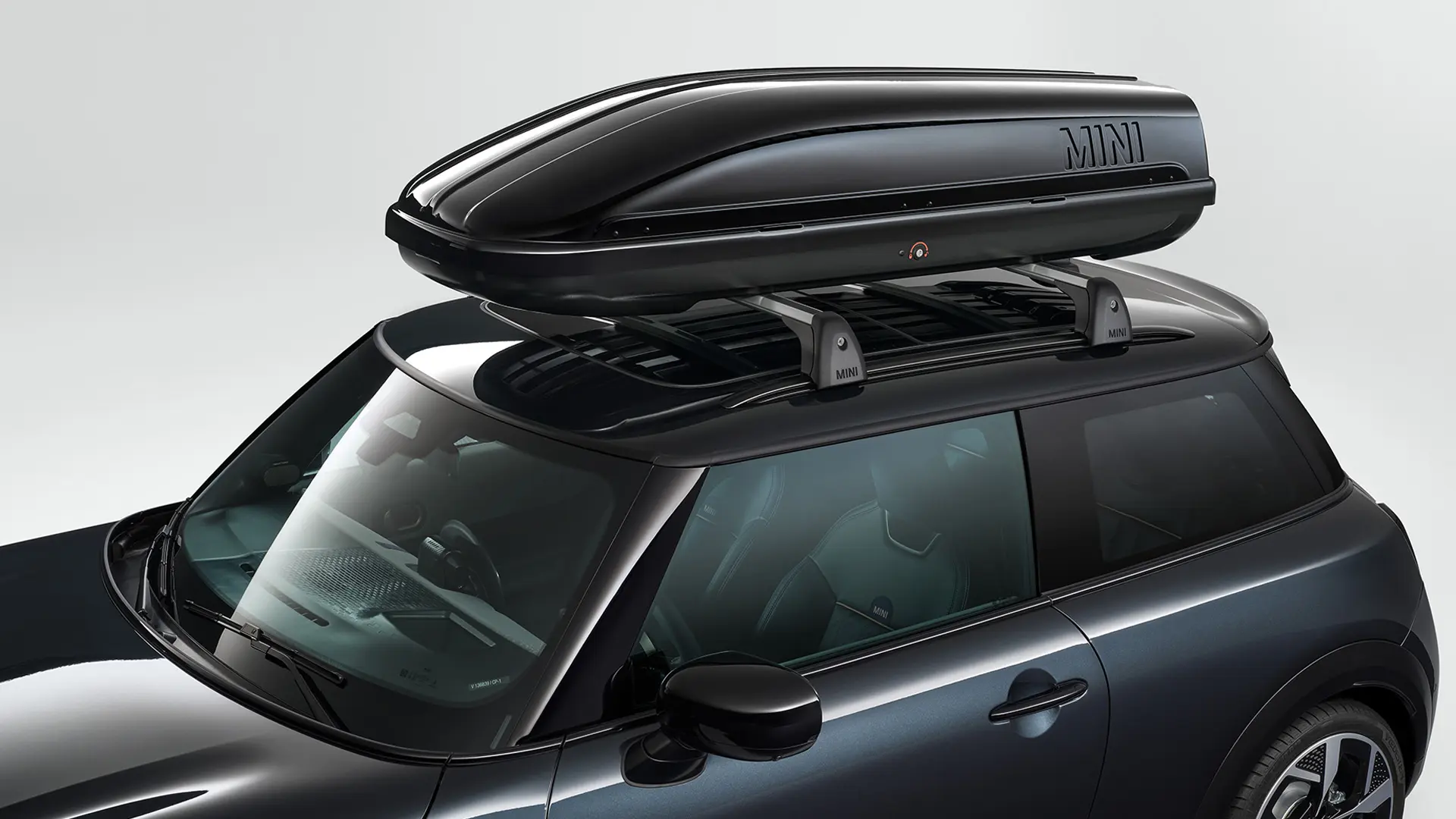 Egy fekete 3 ajtós MINI Cooper fekete MINI 320 tetőboxszal.