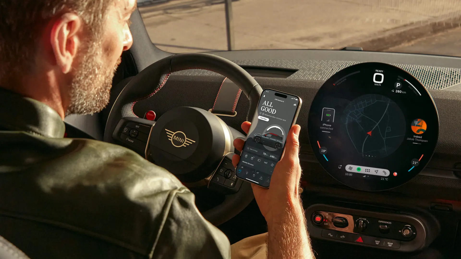 Egy MINI-t vezető személy a MINI alkalmazást használja a telefonján a navigációhoz.