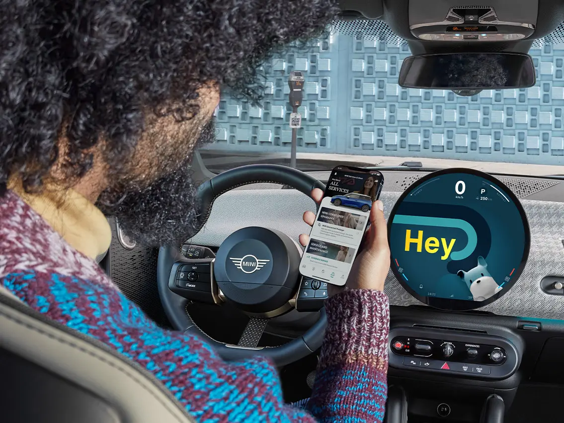 Egy férfi ül egy MINI-ben és a telefonját nézi