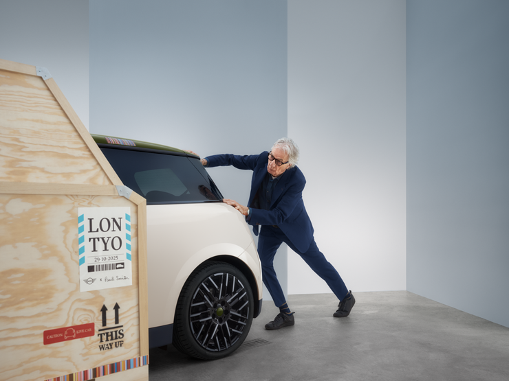 Az Inspired White fényezésű, tisztán elektromos MINI Cooper Paul Smith Edition hátulnézetből – Paul Smith az autó mögött áll