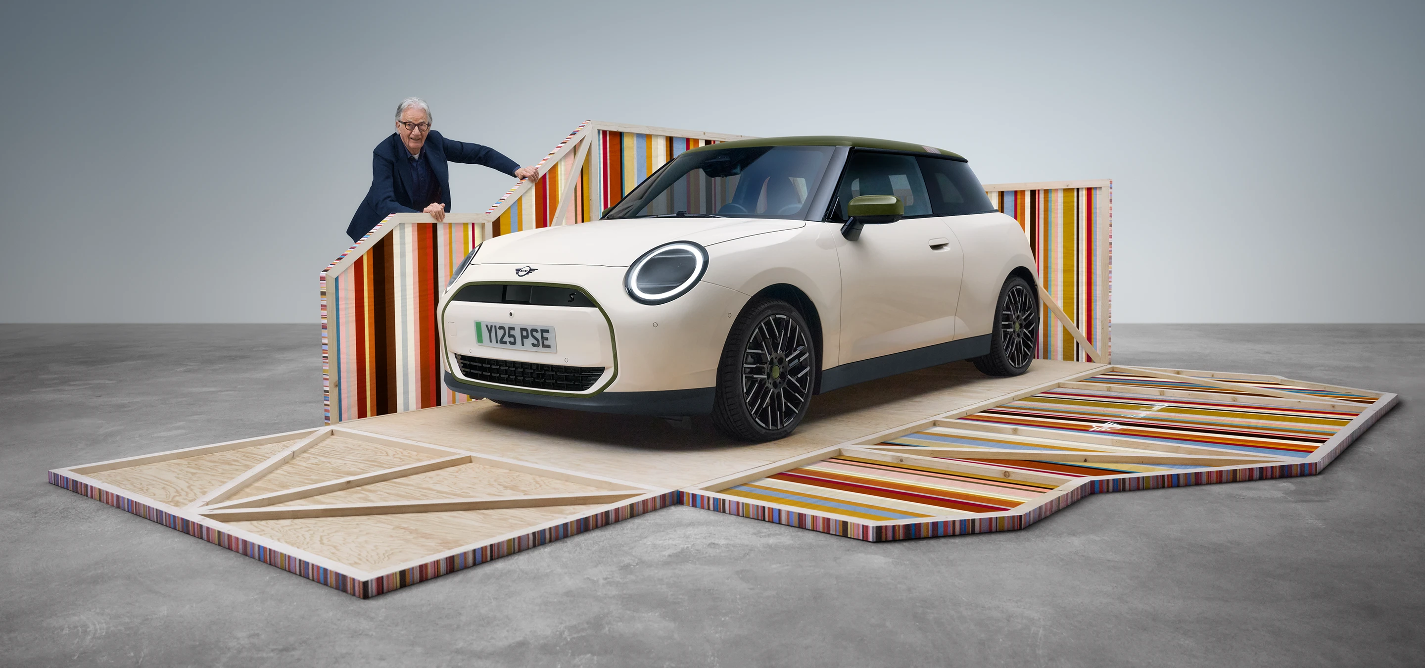 A tisztán elektromos, Inspired White fényezésű MINI Cooper Paul Smith Edition első oldalnézete, Paul Smith dizájnerrel